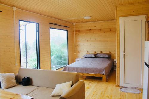 Kottage anania في باتومي: غرفة نوم بسرير واريكة في غرفة