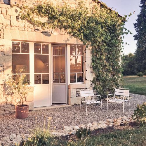 deux chaises assises devant un bâtiment dans l'établissement La Nuit & Le Jour, à Vertheuil-en-Médoc