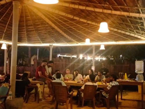 a group of people sitting at tables in a restaurant at Revibe Beach Hostel Gokarna in Gokarna