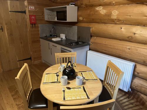 - une table en bois avec des chaises et une bouilloire dans l'établissement Mountain Edge Resort Lodge 2, à Church Stretton