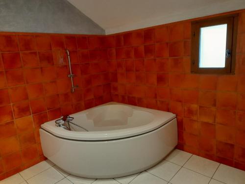 eine weiße Badewanne in einem rot gefliesten Bad in der Unterkunft Gîte à la campagne avec jardin et piscine in Brens