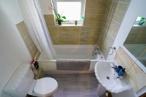 a bathroom with a toilet and a tub and a sink at 3 Bedroom Home in the Dale’s, Very close to Ipswich town centre. in Whitton