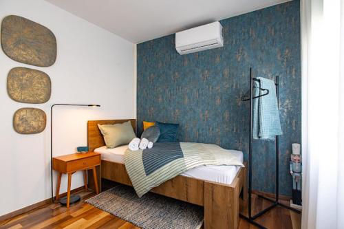 a bedroom with a bed with a blue wall at Apartman Joe in Virovitica