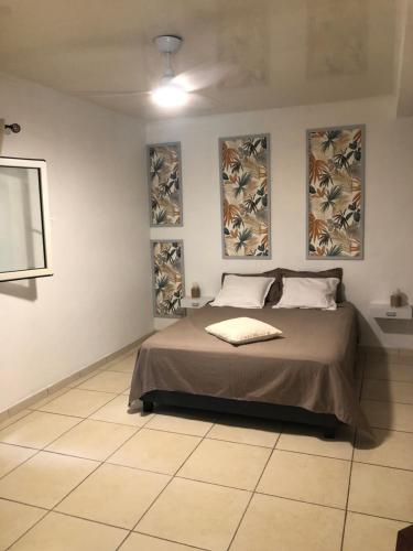 1 dormitorio con 1 cama con 3 cuadros en la pared en Villa Tikoinjoli en Saint-Pierre