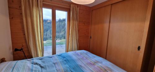 a bedroom with a bed and a large window at Majis 4 in Champoussin