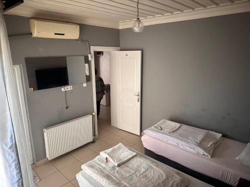 a room with two beds and a tv and a door at sıla pansiyon in Edirne