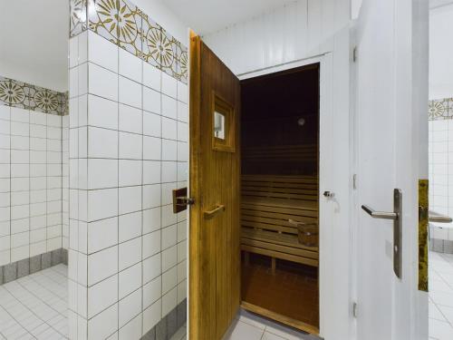 a wooden door in a bathroom with white tiles at Oland Whg11 Sünnenkieker in Wyk auf Föhr