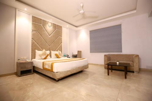 a bedroom with a king sized bed and a chair at Hotel Stanley- Near Delhi Airport in New Delhi