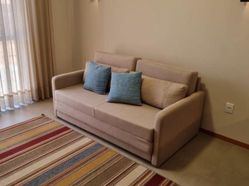 a couch in a living room with two blue pillows at Resort QSB - Um novo padrão de conforto e lazer no coração da cidade in Pirenópolis