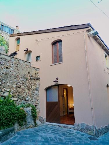 a house with a door and a stone wall at Serendipity Apartment in Castelmola