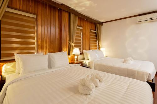 two beds in a hotel room with white sheets at LuangPrabang Center Hotel in Luang Prabang