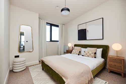 a bedroom with a large bed and a mirror at The South Woodford Place - Adorable 2BDR Flat with Balcony in London