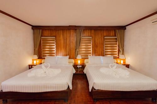 two beds in a room with two windows at LuangPrabang Center Hotel in Luang Prabang