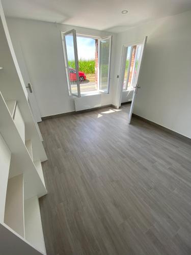 an empty living room with wooden floors and a sliding glass door at La louette in Magny-le-Hongre