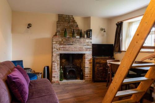 a living room with a brick fireplace and a couch at Adorable and Cosy Tiny Cottage in Heathfield