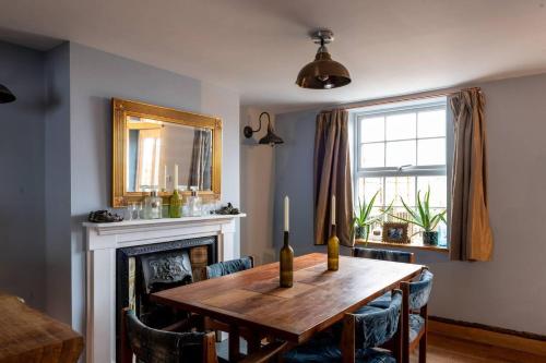a dining room with a wooden table and a fireplace at 3 bedroom Quirky Luxurious Cottage With Hot Tub in Heathfield