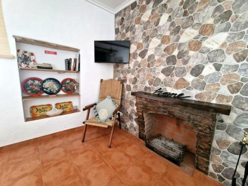 a living room with a stone fireplace and a tv at Casa da Enxota in Póvoa de São Miguel