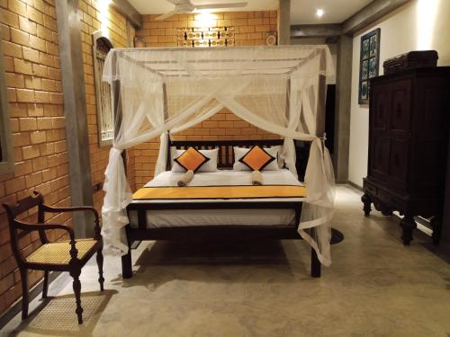 a bedroom with a canopy bed and a chair at The Brick Wonder in Habaraduwa