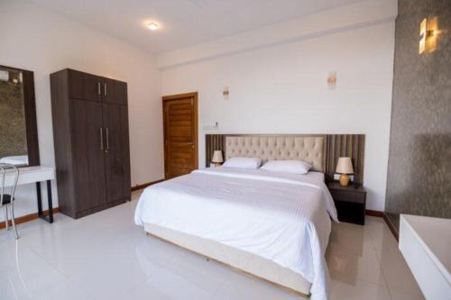 um quarto com uma grande cama branca e uma banheira em Kings Hantana em Kandy