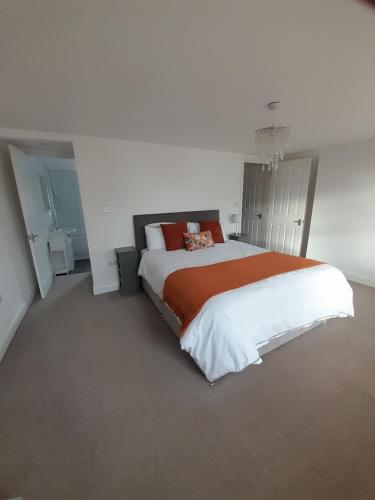 a bedroom with a large bed with an orange blanket at No. 6 The High Street in Royal Wootton Bassett