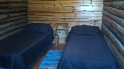 a room with two beds in a log cabin at Balcones del Portezuelo in Potrerillos