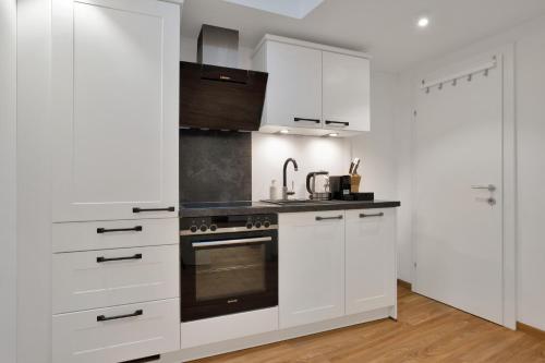 a kitchen with white cabinets and a stove at easy flat Villach main plaza in Villach