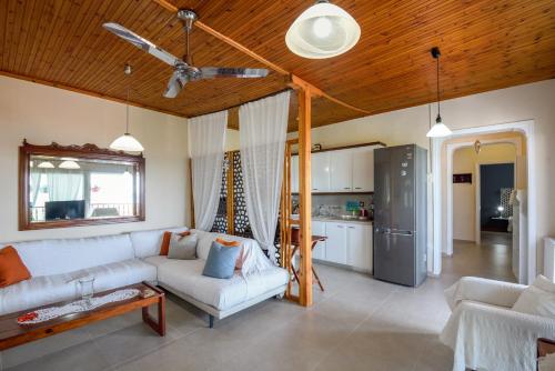 a living room with a white couch and a kitchen at Sophia houses by the sea in Nea Kalikratia