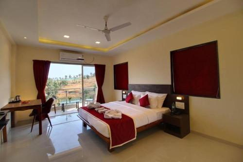 a bedroom with a bed and a desk and a window at Ivy Park Resort in Panchgani