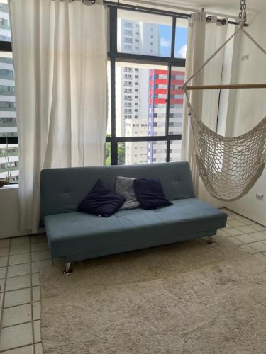 Quarto INDISPONÍVEL NO PRESENTE في ريسيفي: أريكة زرقاء في غرفة المعيشة مع أرجوحة