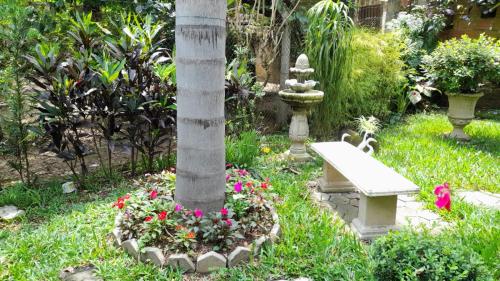 un banco en un jardín con flores alrededor de un poste en Casa & Hospedagem Carol, en Cachoeira Paulista