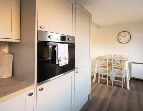 a kitchen with white cabinets and a table with a clock at 22 The Old Market in Yarm