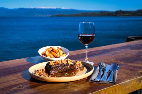 a table with a plate of steak and a glass of wine at Bocalago in Puerto Nuevo