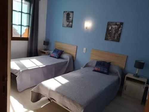 deux lits dans une chambre aux murs bleus dans l'établissement gîte Les Lavandes de Capluc, au Rozier