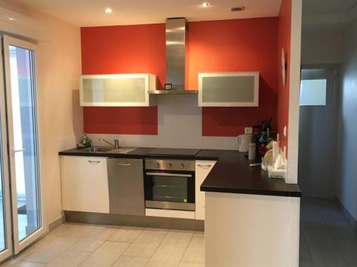 a kitchen with red walls and a stove top oven at Maison 4 pers à 5kms de la plage in Plouider