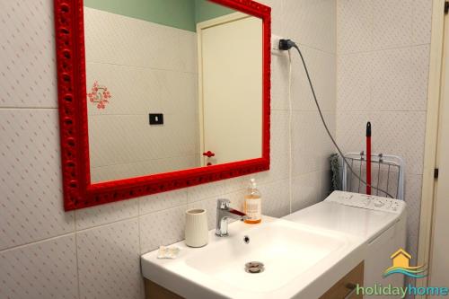 uma casa de banho com um lavatório branco e um espelho vermelho em La Tazza Verde em Arco