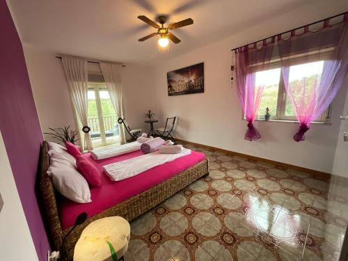 Cette chambre comprend un lit avec des draps roses et un ventilateur. dans l'établissement Casa Vista Etna, 