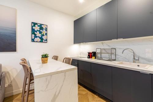 une cuisine avec des armoires noires et blanches et un évier dans l'établissement Appartement moderne pour 4 proche Arc de Triomphe, à Paris