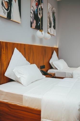 two beds in a hotel room with white sheets at Burundi Palace Boutique Hotel in Bujumbura