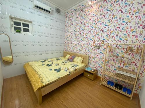 a bedroom with a bed and a wall covered in letters at Villa sân vườn Misa in Phan Thiet