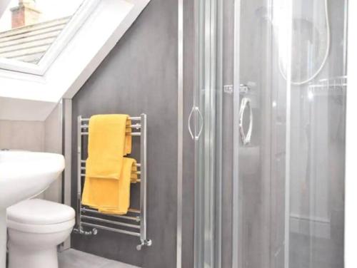 a bathroom with a shower and a yellow towel at Eastfield Lodge with Hot Tub in Stannington