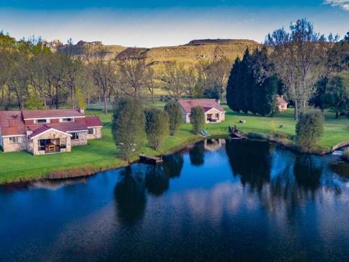 - une vue aérienne sur une maison à côté d'un lac dans l'établissement Lake Naverone Holiday Cottages, à Drakensberg Garden