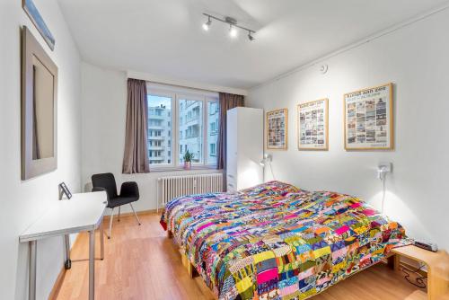 Appartement aan Zee Oostende في أوستند: غرفة نوم بسرير ومكتب وطاولة