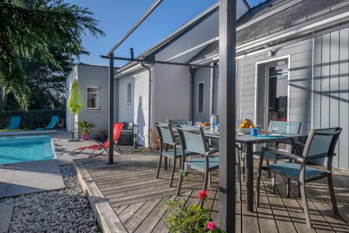 un patio avec une table et des chaises à côté d'une piscine dans l'établissement Séjour confort avec piscine - 6 adultes, 3 enfants, à La Turballe