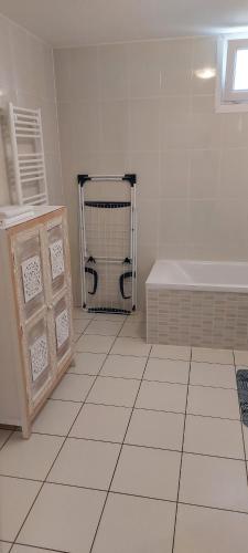 a bathroom with a tub and a white tile floor at Gîte chaleureux le Petit Mauze in Nouaillé-Maupertuis