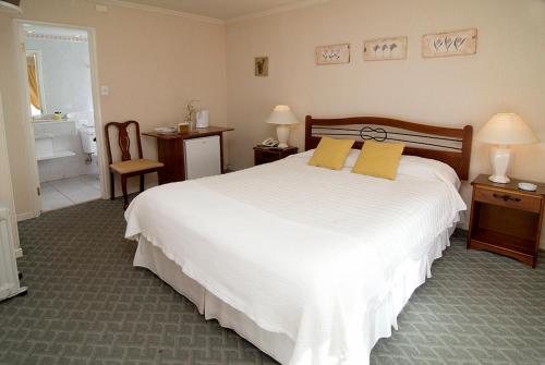 a bedroom with a large white bed and a bathroom at Apart Hotel Casablanca in Valdivia