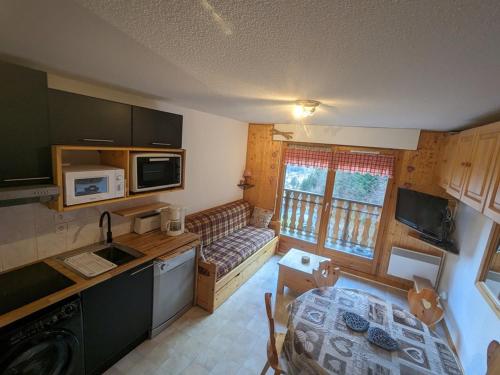 une petite cuisine avec une table et un canapé. dans l'établissement Duplex 3 pièces proche pistes avec balcon et parking - FR-1-573-76, à Saint-Jean-dʼAulps