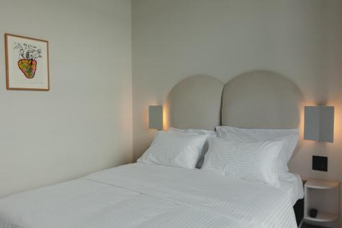a bedroom with a white bed with white pillows at Plexi Space in Athens