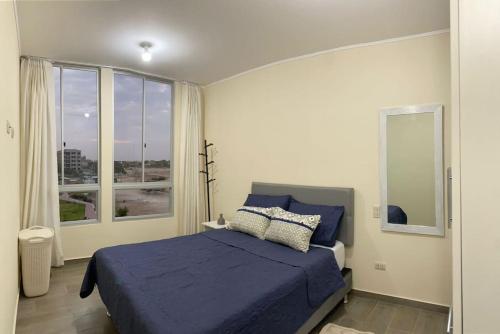 ein Schlafzimmer mit einem blauen Bett und einem großen Fenster in der Unterkunft Departamento de Estreno SEMREQ in Piura