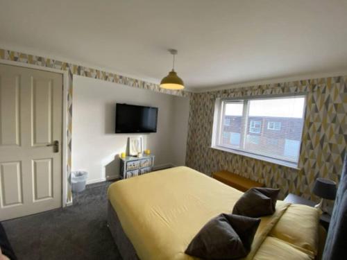a bedroom with a bed and a window and a television at Vibrant 1st Floor Apartment in Cramlington