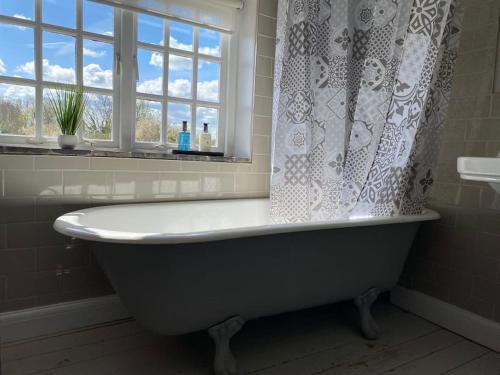 y baño con bañera y ventana. en Shardlow Cottage, en Derby